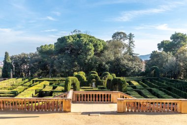 Düzgün budanmış çitleri, klasik heykelleri ve manzaralı parkı olan simetrik bir bahçe..