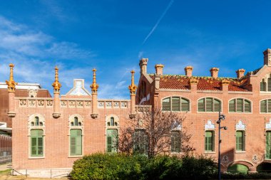 Sant Pau kompleksinde kemerli pencereleri, yeşil panjurları ve dekoratif çatı unsurları olan tarihi bir bina..