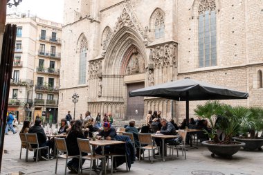 Barselona, Katalonya - İspanya - 01-06-2025: Santa Maria del Mar 'ın önünde insanların yemek yediği bir açık kafe, Gotik kilise girişini ve tarihi kentsel çevreleri gösteriyor.