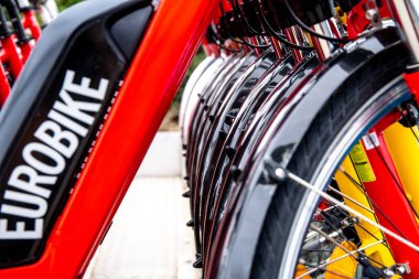 Close view of the side of Eurobike electric bicycles, emphasizing the tires, black battery cases, and vivid red frames. clipart