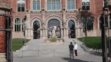 Barselona, Katalonya - İspanya - 01-08-2025: Detaylı kemerleri, heykelleri, boyalı camları ve saat kulesini vurgulayan modernist bir mimari olan Sant Pau 'nun girişinin dikey tavası.