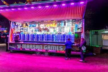 Barselona, Katalonya - İspanya - 01-07-2025: Bir gece karnavalında bir dizi ödül, atari oyunları ve neon ışıklı açık bir panayır standı.