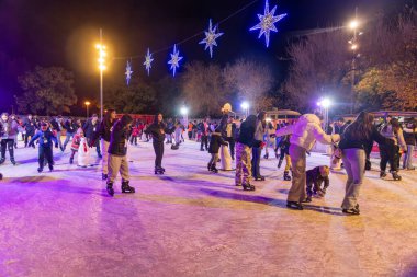 Barselona, Katalonya - İspanya - 01-07-2025: Bir gecede şenlikli mavi yıldız ışıkları altında kayan insanlarla dolu canlı bir açık hava buz pateni pisti.