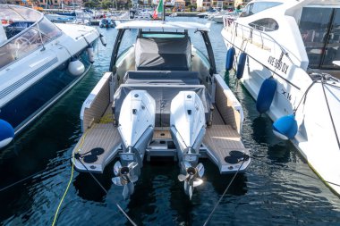 Palau - Sardinien - Italien - 02-19-2025: Palau limanına çift motorlu sürat teknesi yanaştı, yatlarla çevrili, sakin sularda ve arkadaki binalarda yansımalar var.