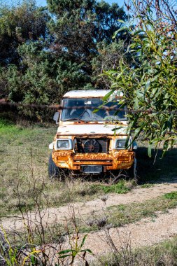SArchittu - Sardinien - Italien - 03-02-2025: Güneşli bir günde Sardinya 'da yakalanan aşırı gelişmiş çimenler ve ağaçlarla çevrili paslı bir off-road aracının ön görüntüsü.