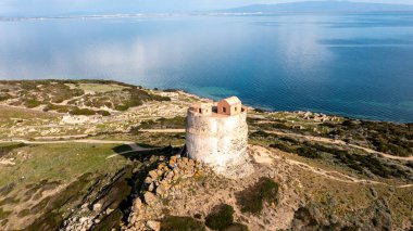 San Giovanni di Sinis - Sardinien - Italien - 03-03-2025: Arka planda Akdeniz bulunan San Giovanni di Sinis yakınlarındaki bir kıyı kulesinin havadan görünüşü. Kule kayalık araziyle çevrili..