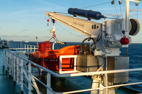 Barcelona, Katalonya - İspanya - 01-10-2025: Turuncu filika, akşam güneşi altında MN CRUISE ROMA ile işaretlenmiş, denizdeki feribot güvertesinde beyaz bir vinçle güvence altına alındı.