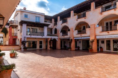 Porto Cervo - Sardinien - Italien - 02-22-2025: Porto Cervo, Sardinya 'daki Akdeniz avlusu, pastel renkli binalar, atari salonları, balkonlar, dükkanlar ve terracotta zeminleri.