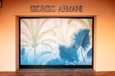 Porto Cervo - Sardinien - Italien - 02-22-2025: Porto Cervo 'da Giorgio Armani mağaza vitrininde mavi ve bej renkli tropik palmiye yapraklarıyla dekoratif bir vitrin görüntüsü yer alıyor.