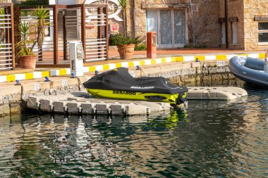 Portisco - Sardinien - Italien - 02-23-2025: Sardinya 'nın Portisco kentindeki limanda bej rengi bir rıhtımda siyah bir koruyucu kapakla kaplı Sea-Doo jet ski.