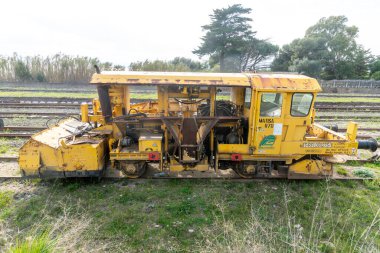 Golfo Aranci - Sardinien - Italien - 02-24-2025: Demiryolu hattındaki Sarı Matisa R7D bakım aracı, mekanik parçaları, taksi bölümünü ve teknik etiketleri gösteriyor.