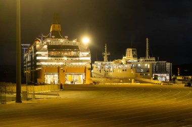 Golfo Aranci - Sardinien - Italien - 02-24-2025: Gece limana yanaşan iki feribot görünür rampalar, aydınlatma yapıları ve Golfo Aranci, Sardinya 'da açık yükleme alanlarıyla.