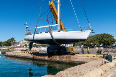 Cagliari - Sardinien - Italien - 03-10-2025: Beyaz bir yelkenli vinci bir vinç tarafından bir limanın suyuna sokuldu.