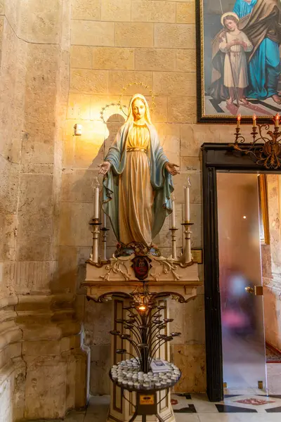 Cagliari - Sardinien - Italien - 03-11-2025: Cattedrale di Santa Maria Assunta e Santa Cecilia 'daki Bakire Meryem Anıtı, mumlarla aydınlatılmış, adak duruşu ve aşağıda dekoratif unsurlarla.