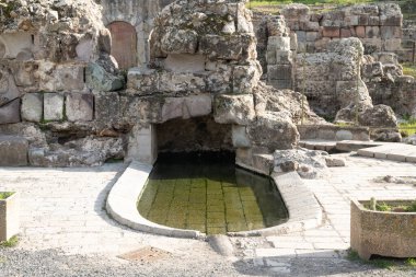 Fordongianus - Sardinien - Italien - 03-04-2025: Kısmen korunmuş bir arkeolojik alandaki yıpranmış bloklardan inşa edilmiş havzalı ve kemerli antik Roma kaplıcası.
