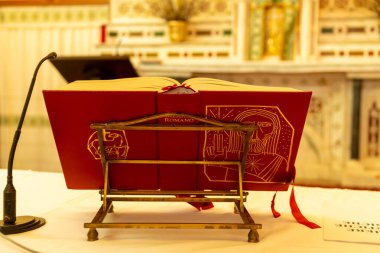 Fordongianus - Sardinien - Italien - 03-04-2025: Açık Roma Missal San Pietro Apostolo kilisesinin sunağının önündeki pirinç kitaplığa yerleştirilmiş bir mikrofon ile.