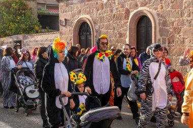 Fordongianus - Sardinien - Italien - 03-04-2025: Renkli hayvan tulumları giymiş yetişkinler ve çocuklar, güpegündüz düzenlenen festival karnaval yürüyüşü sırasında sokakta yürürler.