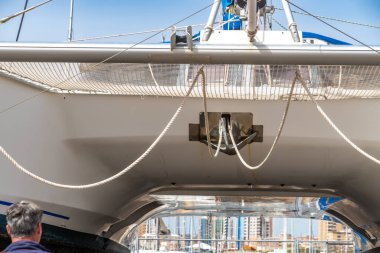 Cagliari - Sardinien - Italien - 03-14-2025: Liman ortamında gün ışığı altında gerilmiş ağlar ve çapa halatı düzeniyle katamaran manzarası.