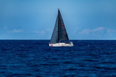 Palermo - Sizilien - Italien - 03-16-2025: Sakin sularla çevrili açık bir gökyüzü altında derin mavi denizde süzülen siyah yelkenli bir tekne.