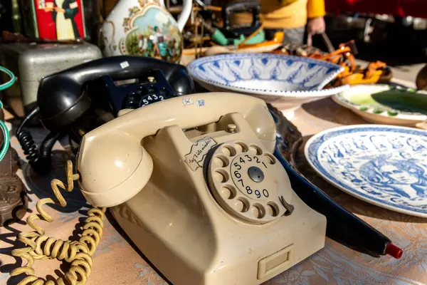 Jalon, Alicante - İspanya - 12-14-2024: Klasik arama dizaynları ve doğal ışık kablolarının yer aldığı antika bir pazar masasında sergilenen antika döner telefon koleksiyonu.