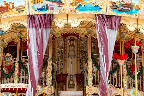 Reus, Katalonya - İspanya - 01-03-2025: Süslü süslemeler, altın oymalar, boyanmış paneller ve şenlikli kırmızı çiçeklerin yer aldığı klasik bir çift katlı atlıkarınca.