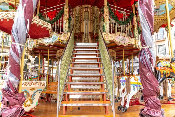 Reus, Katalonya - İspanya - 01-03-2025: Büyük bir merdiven, süslü dekorasyonlar, ışıklar ve şenlikli çelenklerle süslenmiş, klasik bir çift katlı atlıkarıncanın üst katına çıkıyor.