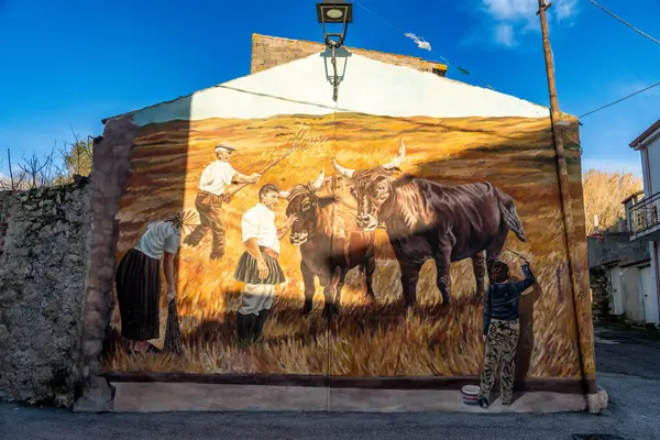 Semestene, Sardinya - İtalya - 01-12-2025: Öküz ve işçilerle geleneksel çiftçiliği resmeden bir duvar resmi. Sanat eserleri güneş ışığında bir binanın ön cephesine boyanmış..