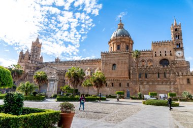 Palermo - Sizilien - Italien - 03-18-2025: Kubbesi, saat kulesi ve yemyeşil bahçesi ile Palermo Katedrali 'nin ön görüntüsü, dağınık bulutlarla dolu açık mavi bir gökyüzü altında yakalanmıştır..
