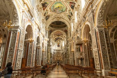 Palermo - Sizilien - Italien - 03-18-2025: Palermo 'daki Chiesa del Gesu barok iç mimarisi fresk tavan, mermer sütunlar, avizeler, ahşap sıralar ve çok sayıda oturan ziyaretçi.