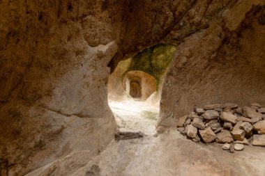 Sperlinga - Sizilien - Italien - 03-25-2025: Kaya geçidi doğal olarak oyulmuş duvarlar, uzak kemer yolu ve Burg Sperlinga, Sicilya 'da yumuşak doğal ışıkla aydınlatılmış taş yığını.