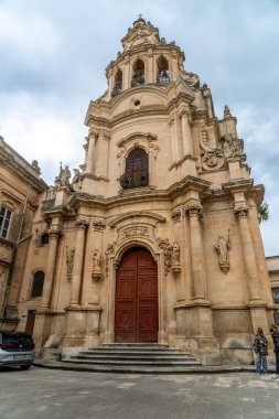 Ragusa, Sizilien - İtalya - 04-03-2025: Ragusa 'daki San Giuseppe Kilisesi' nin önünde ayrıntılı bir barok cephesi, süslü heykeller, kemerli kapılar ve taş basamaklar yer alıyor.