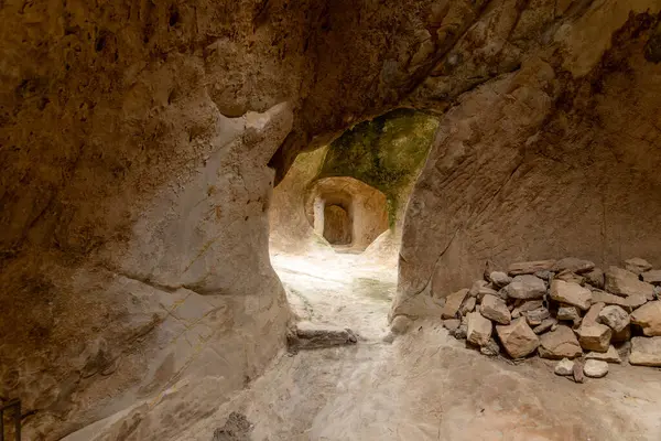 Sperlinga - Sizilien - Italien - 03-25-2025: Kaya geçidi doğal olarak oyulmuş duvarlar, uzak kemer yolu ve Burg Sperlinga, Sicilya 'da yumuşak doğal ışıkla aydınlatılmış taş yığını.