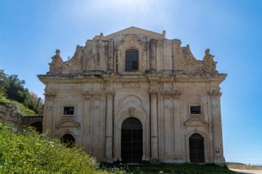 Scicli, Sizilien - İtalya - 04-05-2025: Scicli 'deki San Matteo Kilisesi cephesinde süslü taş işçiliği, kemerli kapı araları, sütunlar ve açık mavi gökyüzü altında ayrıntılı mimari yer alıyor.