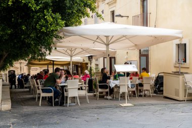 Pantalica, Sizilien - İtalya - 04-11-2025: Pantalica 'da güneşli bir yolda yeşil alanla çevrili Galleria Cascitita adlı taş tünelin girişine iki yürüyüşçü yaklaşıyor