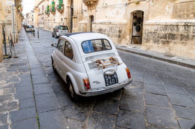 Noto, Sizilien - İtalya - 04-06-2025: Arkasında tarihi binalar bulunan kaldırım taşı bir sokakta park edilmiş eski bir Fiat 500 'ün arka görüntüsü. Noto 'da Yakalandı.
