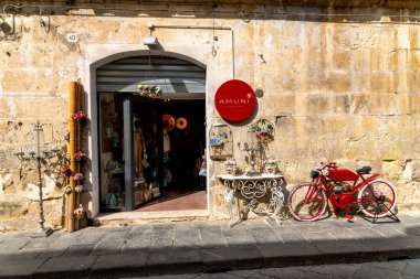 Pantalica, Sizilien - İtalya - 04-11-2025: Pantalica 'da güneşli bir yolda yeşil alanla çevrili Galleria Cascitita adlı taş tünelin girişine iki yürüyüşçü yaklaşıyor