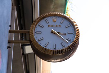 Syrakus, Sizilien - İtalya - 04-08-2025: Siraküza 'daki bir binanın ön cephesine yerleştirilmiş altın çerçeveli Rolex saat, beyaz kadranlı, altın aksanlı ve açık hava arka planlı.