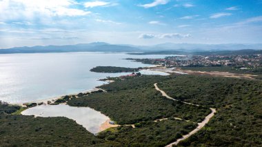 Nodu Pianu 'nun kıyı şeridini, bitki örtüsünü, plajları ve mavi gökyüzünün altında dağları olan küçük bir kasabayı gösteren hava manzarası..