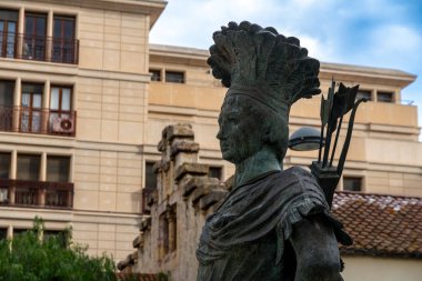 Bronz heykelin başı * El Gegant Indi * geleneksel giysiler ve oklar içinde uzun bir figür içerir. Heykel Reus 'ta halka açık bir meydanda duruyor..