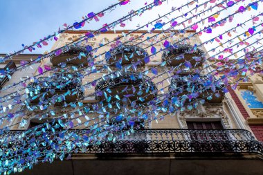 Süslü balkonları ve parlak mavi ve mor yansıtıcı süslemeleri olan tarihi bir binanın alçak açılı görüntüsü..