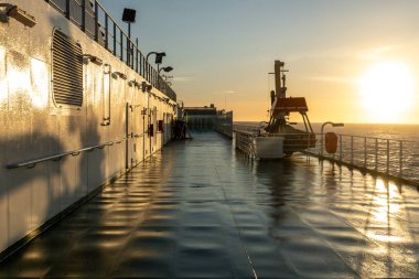 Güneş batarken feribot güvertesine yansıyan güneş, güverte yapılarını, tırabzanları ve deniz ekipmanlarını gösteriyor..