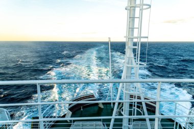 Üst güverteden, feribot yolculuğunun günbatımında açık okyanuslu beyaz korkulukları gösteren görüntüler..
