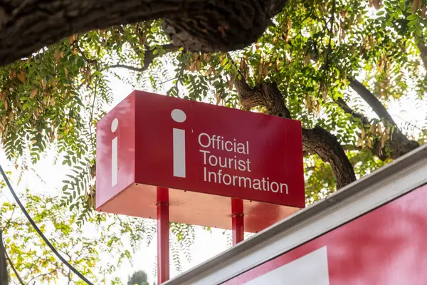 Kalın harflerle kırmızı ve beyaz bir turist bilgilendirme işareti yeşil yaprakların zeminine karşı durarak,