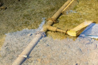 Paslı bir T-kavşak boru hattı Porto Cervo marinasının deniz tabanında uzanıyor, berrak sığ sulardan görülebiliyor ve çökelti ve alglerle kaplı..