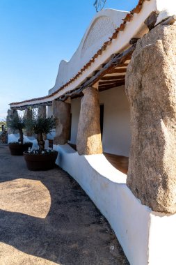 Devasa doğal taş sütunlar, Porto Cervo 'daki Stella Maris Kilisesi' nin girişinde beyazlatılmış bir duvarı ve fayanslı çatıyı destekliyor..