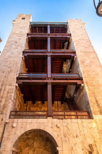 Taş kule yapısı Torre dellElefante. Açık ahşap balkonları ve kemerli girişi var. Aşağıdan görülebiliyor..