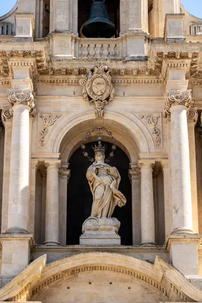 Scicli 'deki San Bartolomeo Kilisesi' nin detaylı görüntüsü süslenmiş heykelleri, sütunları ve açık mavi yay gökyüzünün altındaki çan kulesini gösteriyor..