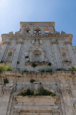 Siraküza 'daki barok kilise cephesinde sütunlar, taş oymalar, kemerli pencereler, çan kulesi ve yapının üzerinde yabani bitkiler var..