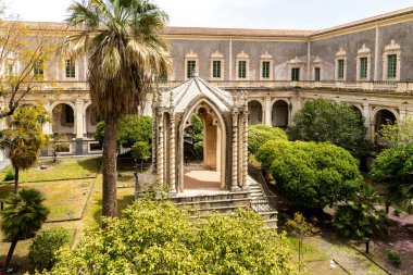 Catania, Sizilien - İtalya - 04-15-2025: Catania, Sicilya, İtalya 'daki San Nicola Manastırı' nın bahçesindeki palmiye ağaçları ve çalılarla çevrili Gotik tarzı pavyon.