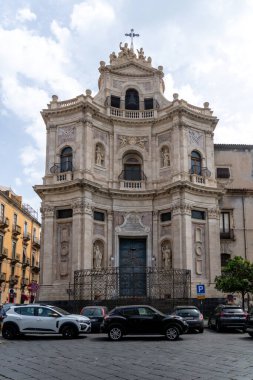 Catania, Sizilien - İtalya - 04-15-2025: Catania, Sicilya 'daki Barok kilise cephesi kemerli pencereler, oyuklar, işlenmiş demir çitler, balkonlar ve taş oymalar.